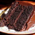 A decadent slice of Moist Chocolate Layer Cake on a colorful plate with a golden fork.
