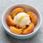 Close-up of baked peaches with golden caramel glaze served on a plate.