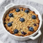 A close-up of a freshly baked lemon blueberry oatmeal dish in a white casserole dish.