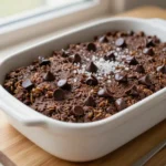 A close-up of brownie baked oatmeal served in a white dish with a fork on the side.