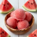 A bowl of vibrant pink watermelon sorbet served in a glass dish, made using the Ninja Creami machine.