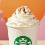 A glass mug filled with a frothy skinny pumpkin spice latte topped with cinnamon.