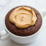 A close-up view of a rich chocolate peanut butter mug cake served in a white ceramic mug.
