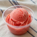 A vibrant bowl of homemade watermelon sorbet made using the Ninja Creami machine, garnished with fresh mint leaves.