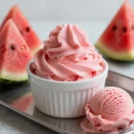 A bowl of homemade watermelon ice cream served with fresh watermelon slices.