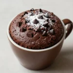 A freshly baked healthy mug cake topped with fresh berries and a drizzle of honey.