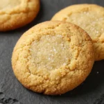A plate of freshly baked golden butter cookies arranged neatly on a wooden table.
