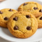 A plate of freshly baked chocolate chip pumpkin cookies on a wooden table.