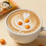 A cup of coffee topped with whipped cream and Pumpkin Spice M&M's on a wooden table.