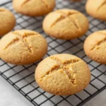 A plate of freshly baked sugar-free peanut butter cookies on a wooden table.