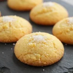 A plate of golden-brown butter cookies arranged neatly on a wooden table.