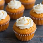 A batch of freshly baked flourless pumpkin muffins on a wooden table.