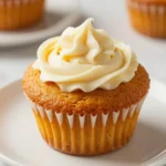 Freshly baked low carb pumpkin muffins with a cream cheese swirl on a wooden table.