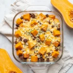 A baked butternut squash casserole with rice and ground beef served in a casserole dish.