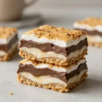 Close-up of homemade S'more bars with graham cracker crust, melted chocolate, and toasted marshmallows on top.