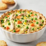 A creamy crock pot chicken pot pie filling with tender chicken, carrots, peas, and potatoes served in a bowl.