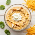 Creamy buffalo chicken dip served in a baking dish with celery sticks and tortilla chips on the side