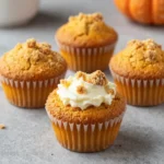 Freshly baked keto pumpkin cream cheese muffins topped with a creamy swirl on a plate
