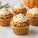 Low carb pumpkin muffins with a cream cheese swirl on top, arranged on a plate.