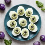 A platter of creepy deviled eggs decorated with olive spiders and paprika for a Halloween party snack