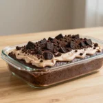 A slice of Oreo dirt cake layered with chocolate pudding, crushed Oreo cookies, and whipped topping in a glass dish.