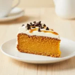 A sliced pumpkin poke cake topped with whipped cream and drizzled caramel on a serving plate.