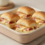 Baked ham and cheese sliders on a tray with melted cheese and golden tops