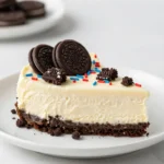 No bake Fireworks Oreo cheesecake bars topped with whipped cream and colorful candy pieces on a white serving plate