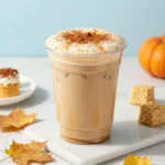 A glass of iced pumpkin cream chai tea latte topped with whipped pumpkin cream and cinnamon over ice