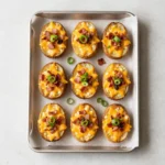 Crispy baked potato skins topped with melted cheese, crispy bacon, and chopped green onions on a serving platter.