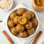 A plate of pumpkin protein balls dusted with cinnamon, made with gluten-free and vegan ingredients.